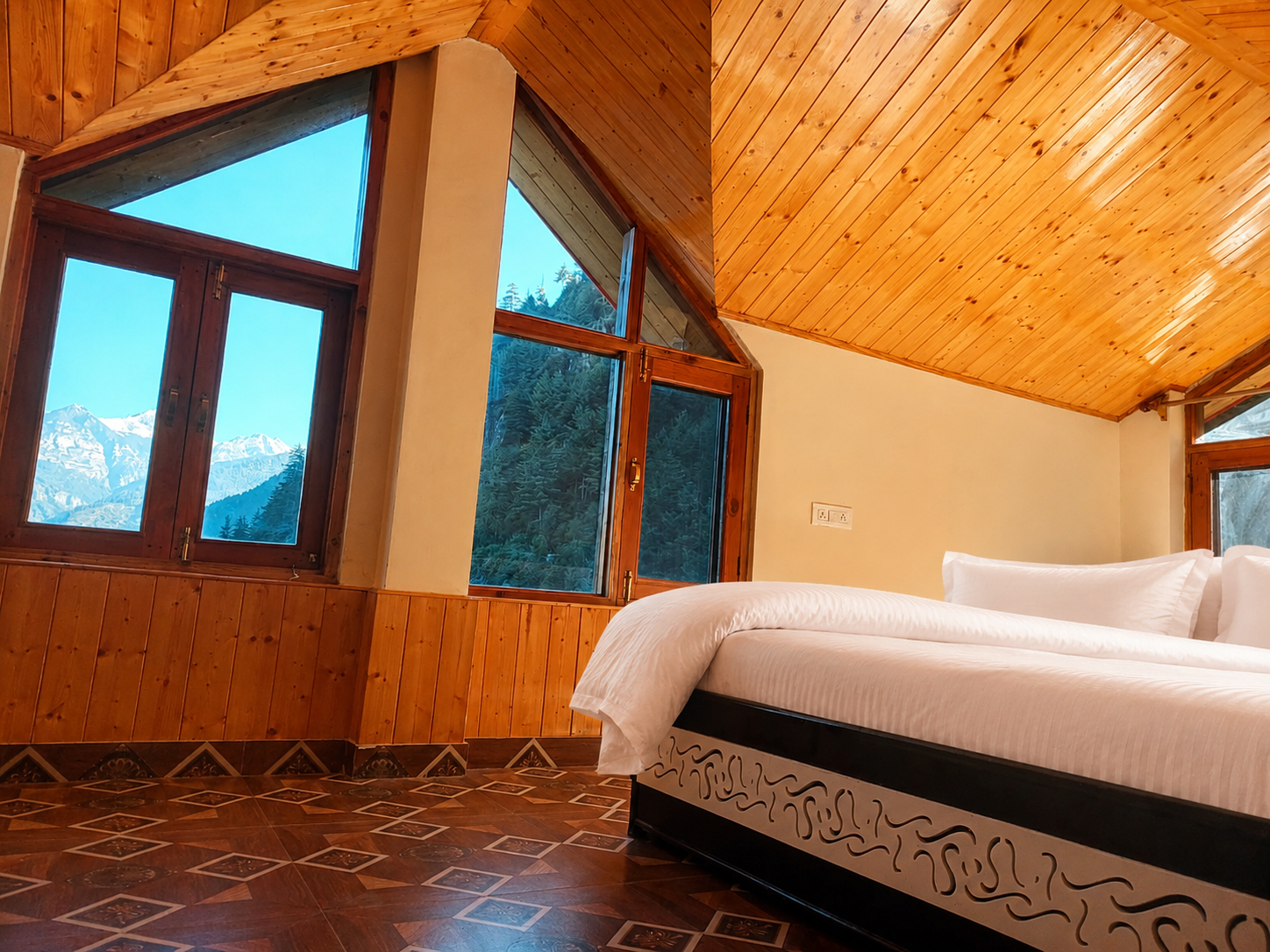 Boutique cabin bedroom with timber ceiling and a Himalayan view through tall windows