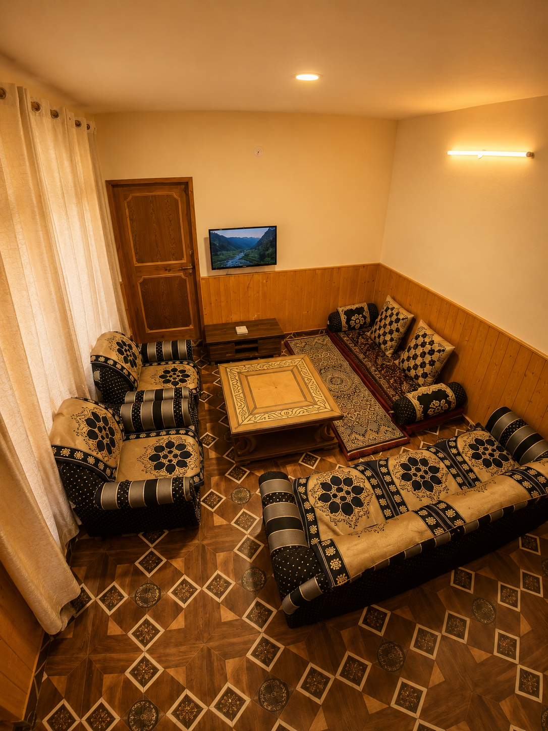 The common sitting room with low sofas, timber wainscot and warm lamps